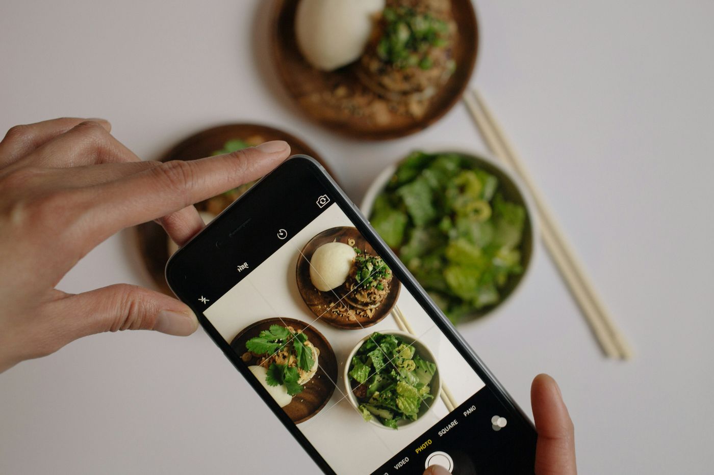 Someone photographing plates of food with a phone for social media